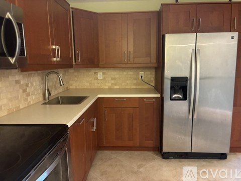 A kitchen with wooden cabinets and a stainless steel refrigerator.