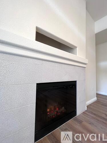 A white fireplace with a wood burning fire inside.