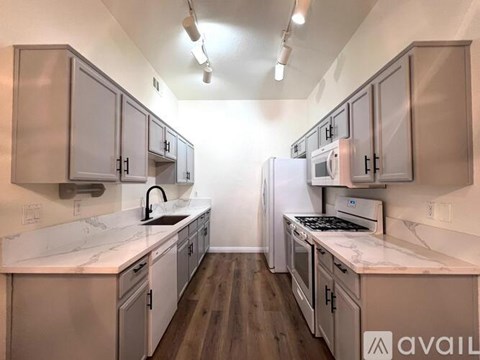 A kitchen with white cabinets and a marble countertop.