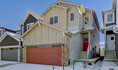 A house with a red garage door in the snow.