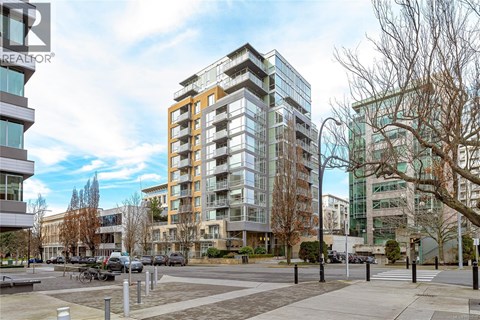 A modern apartment building with a parking lot in front.