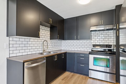 A modern kitchen with black cabinets and a stainless steel oven.