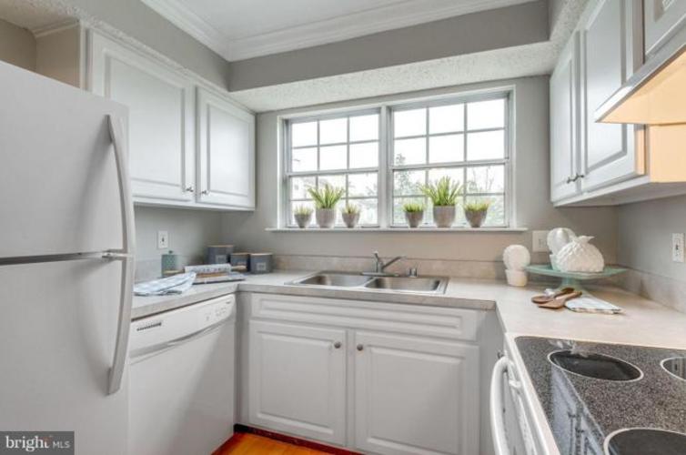 A kitchen with white cabinets and a refrigerator.