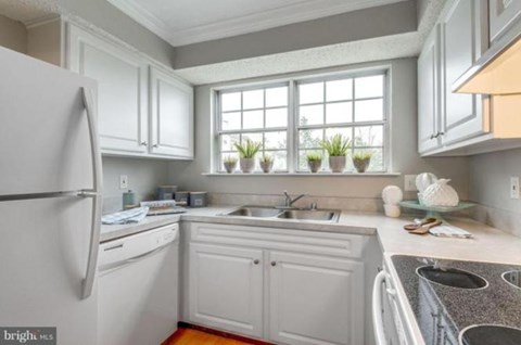 A kitchen with white cabinets and a refrigerator.
