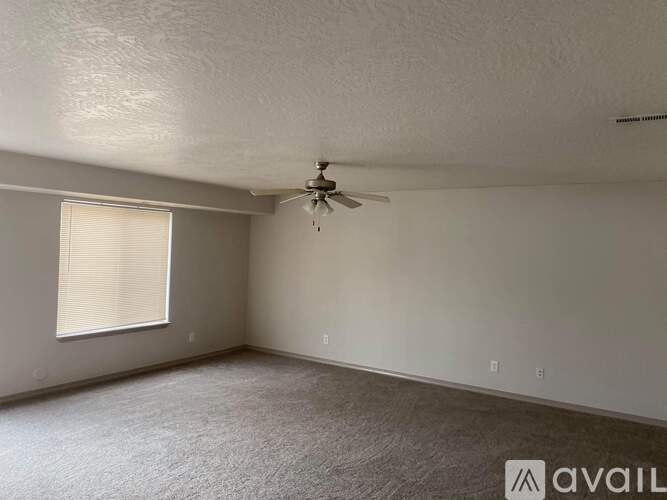 A room with a ceiling fan and a window with blinds.