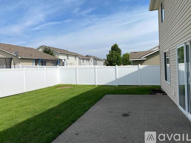 A white fence separates a grassy area from a building.