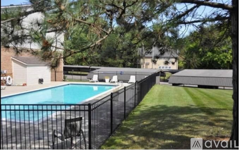 A pool surrounded by a black fence with a house in the background.