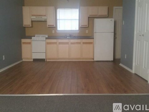 A kitchen with white appliances and wooden floors.