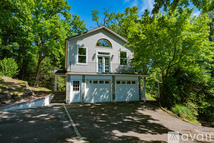A two-story house with a garage is surrounded by trees.