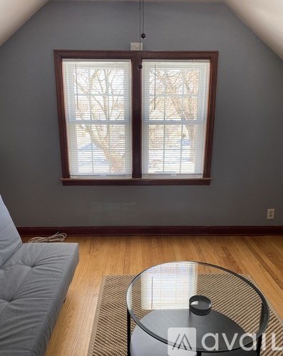 A living room with a grey couch and a glass table with a pot on it.