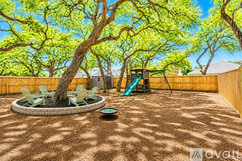 A backyard with a fire pit, chairs, and trees.