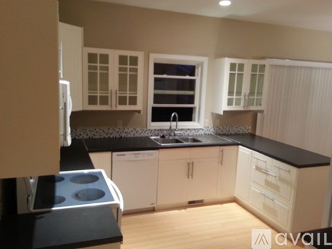 A kitchen with white cabinets and black countertops.