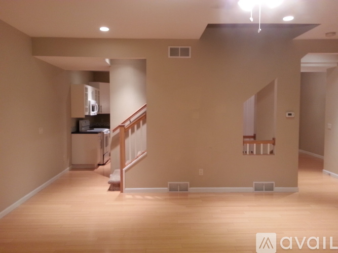 A spacious room with wooden floors and a staircase leading to the upper level.