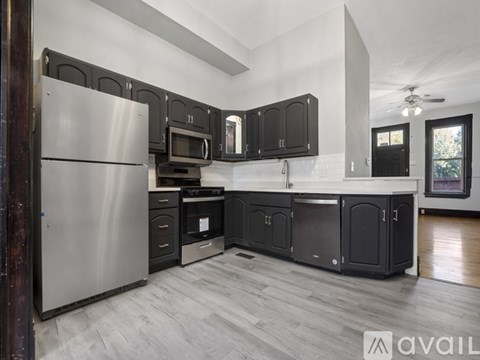 A modern kitchen with a stainless steel refrigerator and black cabinets.