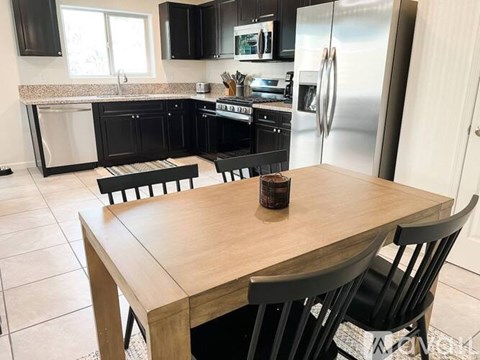 A kitchen with black cabinets and a wooden table.