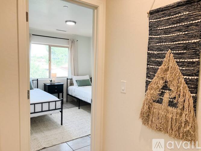 A bedroom with two beds and a woven wall hanging.
