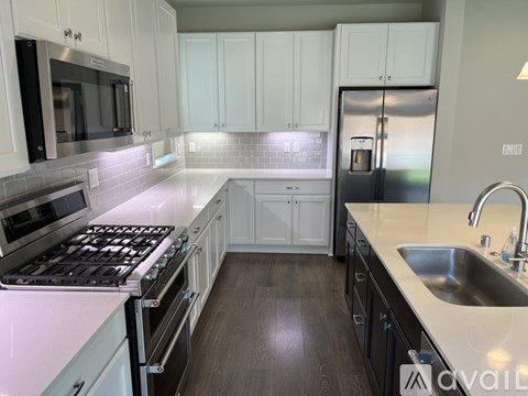 A kitchen with white cabinets and a stainless steel refrigerator.