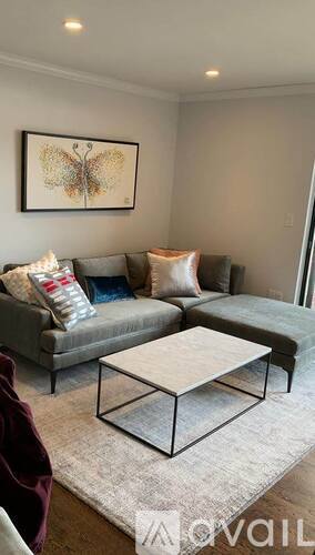 A living room with a grey couch, a coffee table, and a butterfly picture on the wall.
