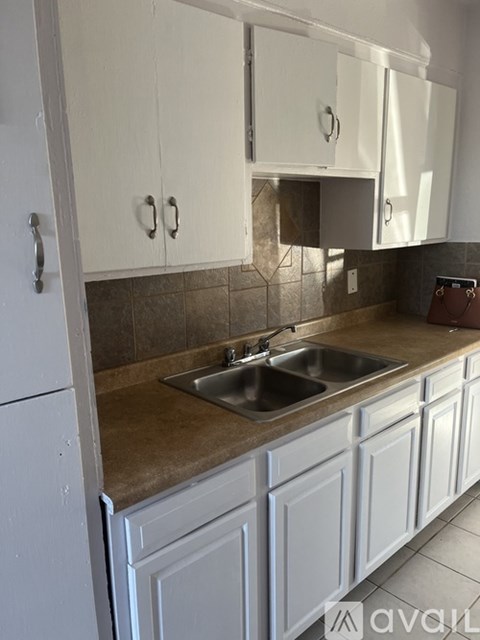 A kitchen with white cabinets and a brown countertop.