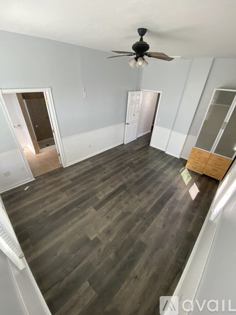 A room with wooden flooring and a ceiling fan.