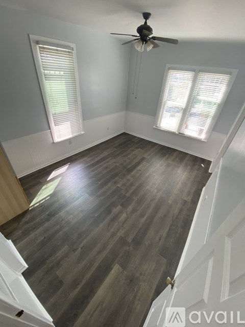 A room with a ceiling fan and two windows with blinds.