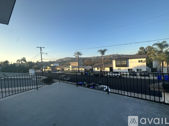 A parking lot with a black fence and a building in the background.