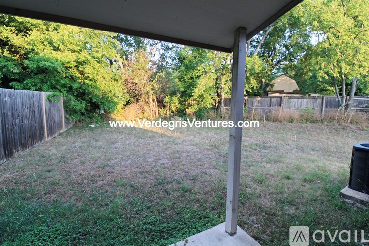 A backyard with a wooden fence and a grassy area.