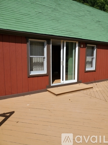 A red house with a green roof and a wooden deck.