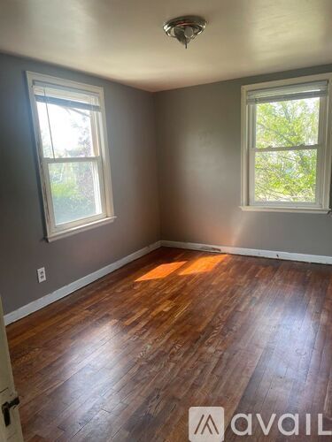 A room with wooden floors and two windows.