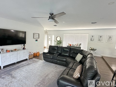 A living room with a black leather couch and a white cabinet.