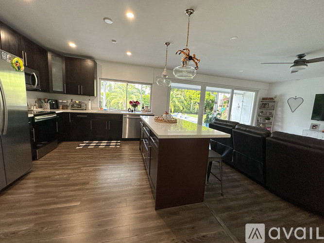 A kitchen with dark wood floors and a large island in the middle.