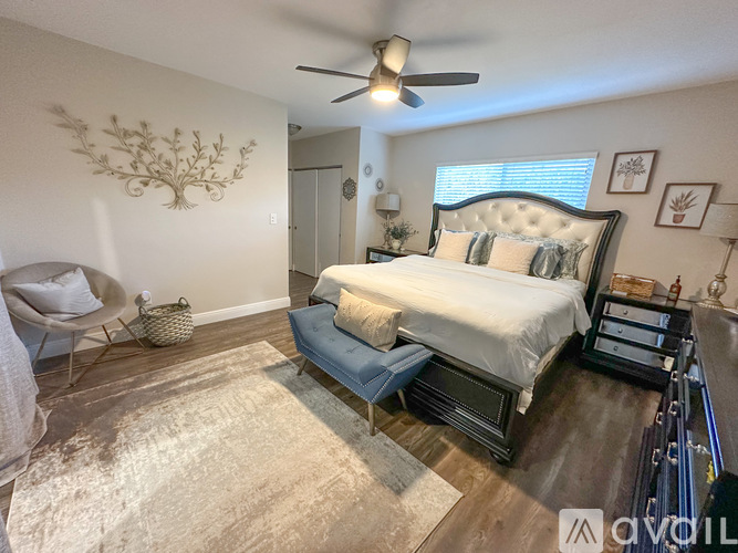 A bedroom with a bed, chair, and a rug.