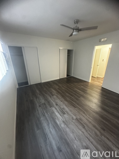 A room with a ceiling fan and wooden flooring.