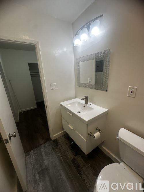 A bathroom with a sink, toilet, and mirror.