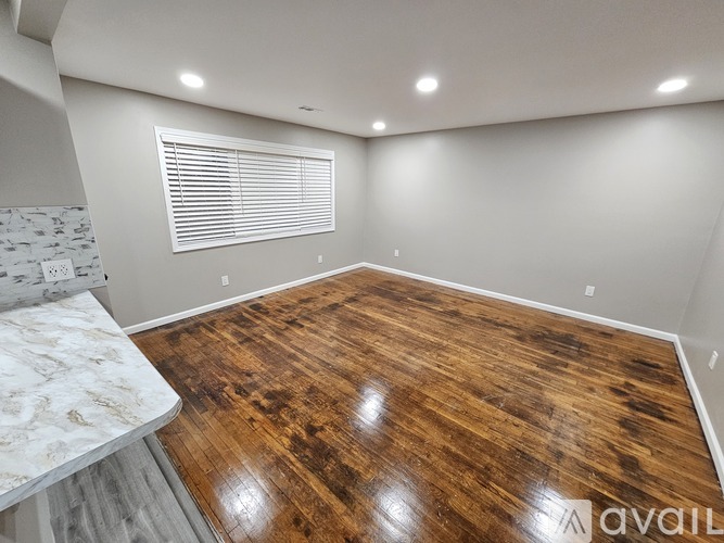 A room with wooden flooring and a window with blinds.