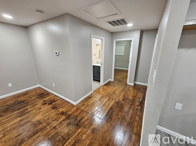 A room with wooden flooring and white walls is available for rent.