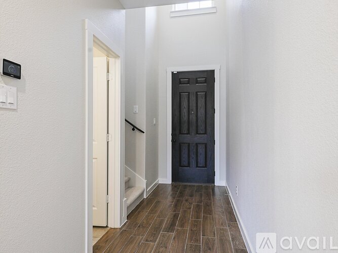 A hallway with a black door and a white door.
