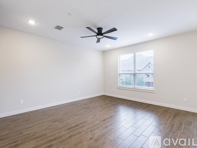 A spacious room with a ceiling fan and wooden flooring.