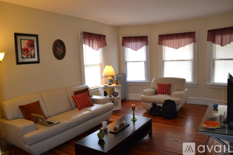 A living room with a white couch, a white chair, and a wooden floor.