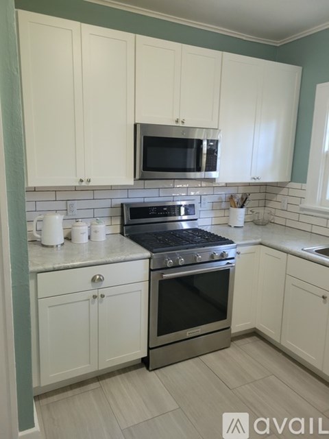 A kitchen with white cabinets and a black stove top oven.