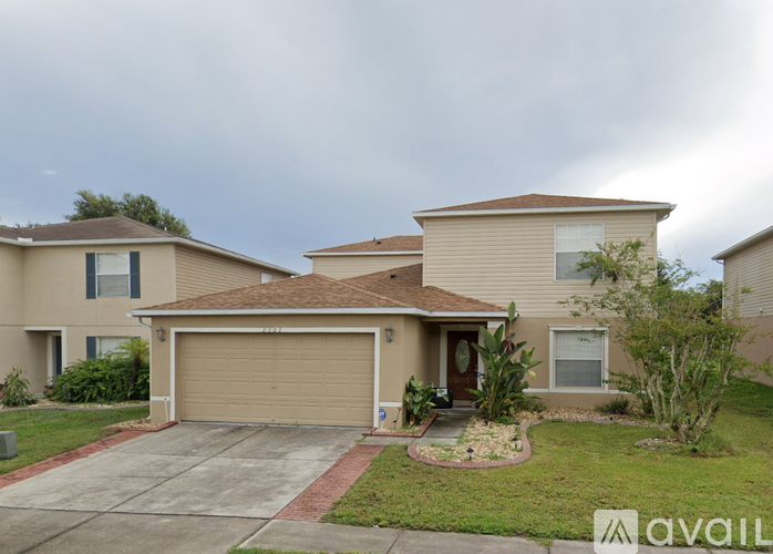 A beige house with a brown roof and a brown garage door.