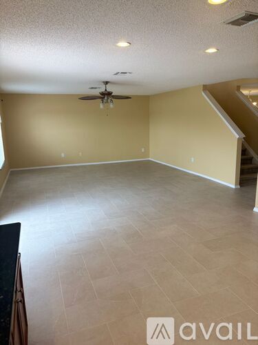 A spacious room with a ceiling fan and lighting fixtures.