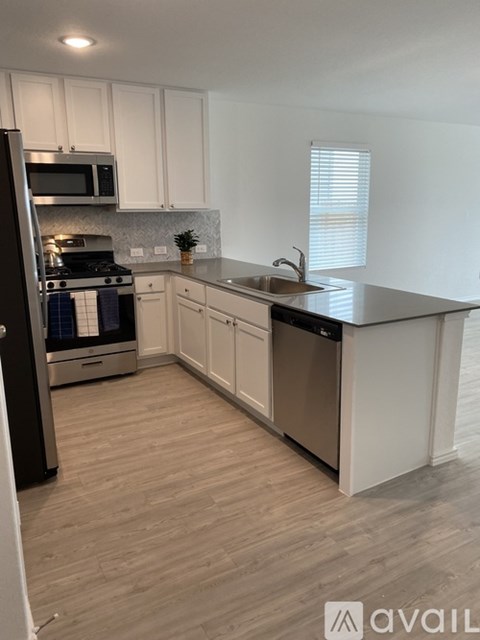 A kitchen with white cabinets and a wooden floor.