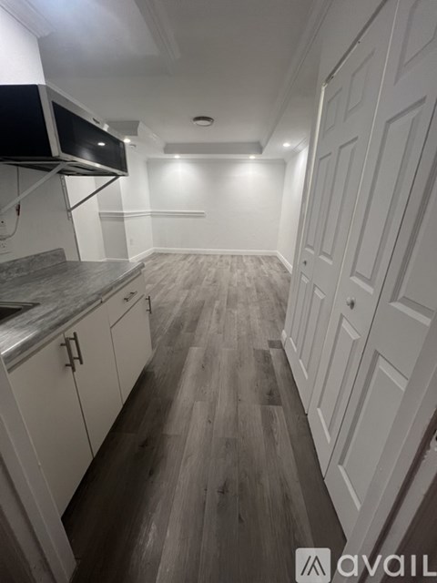 A kitchen with white cabinets and a wooden floor.