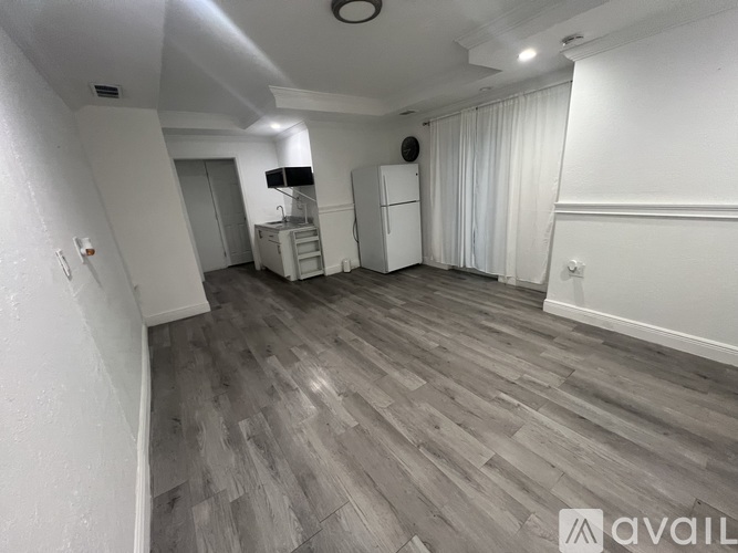 A spacious room with wooden flooring and white walls.
