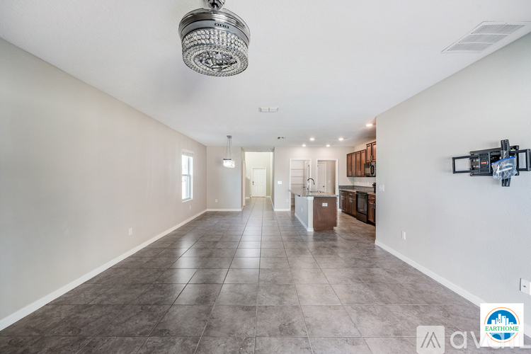 A spacious living room with a large grey floor and a chandelier hanging from the ceiling.