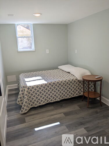 A bedroom with a bed, a small table, and a window.