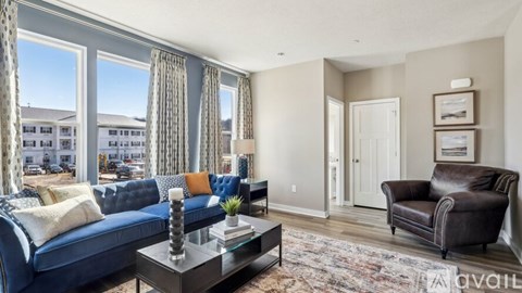 A living room with a blue couch and a brown leather chair.