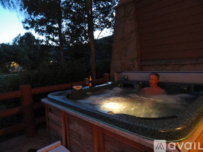 A man is sitting in a hot tub on a deck.