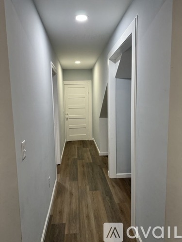 A hallway with wood flooring and white walls.